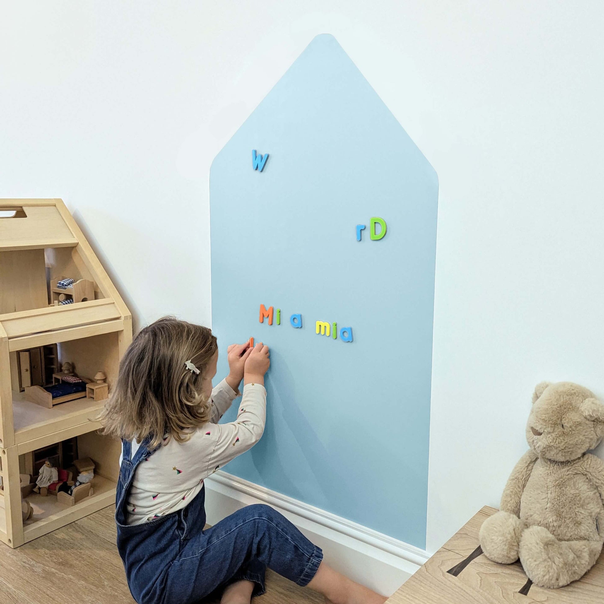 Child playing with magnetic letters on a light blue coloured house shaped wall decal