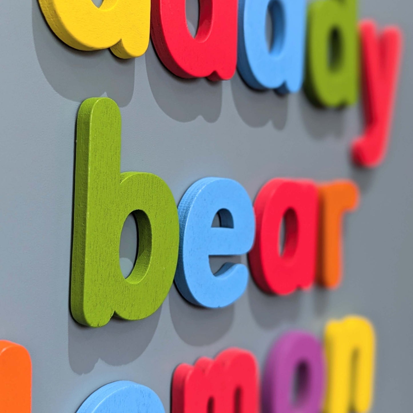 closeup of wooden magnetic letters on a teal background