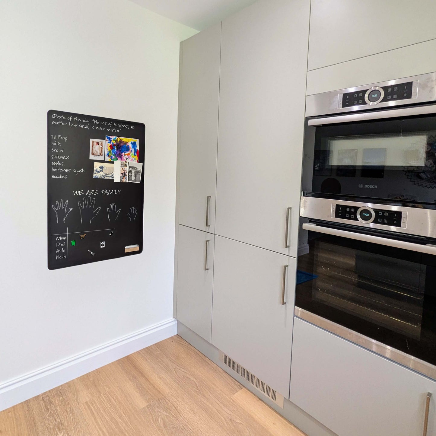 Kitchen with black cooker grey units and black noticeboard on wall